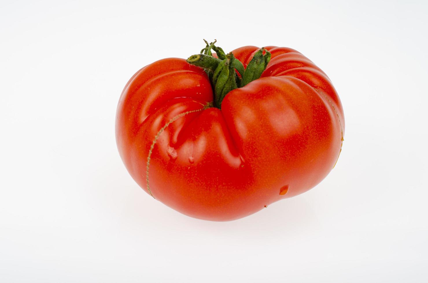 único tomate maduro de carne vermelha isolado no fundo branco. foto de estúdio