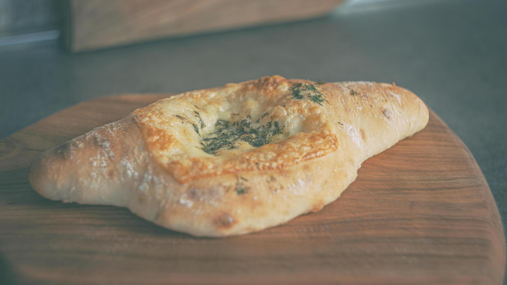 casa cozinha. khachapuri com queijo e aneto em uma de madeira cereja borda foto