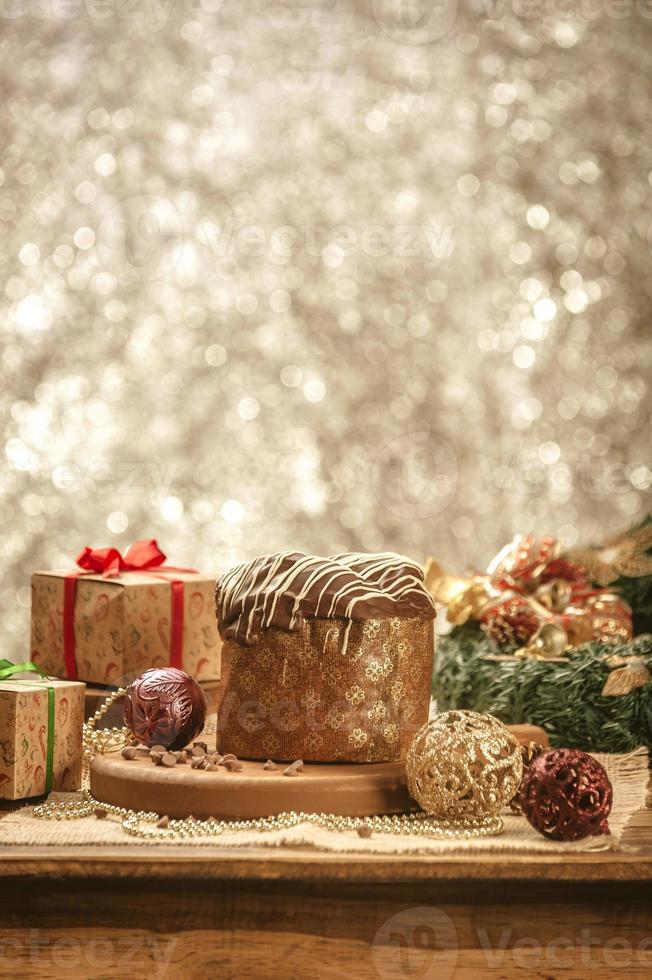 panetone de chocolate na mesa de madeira com enfeites de natal foto