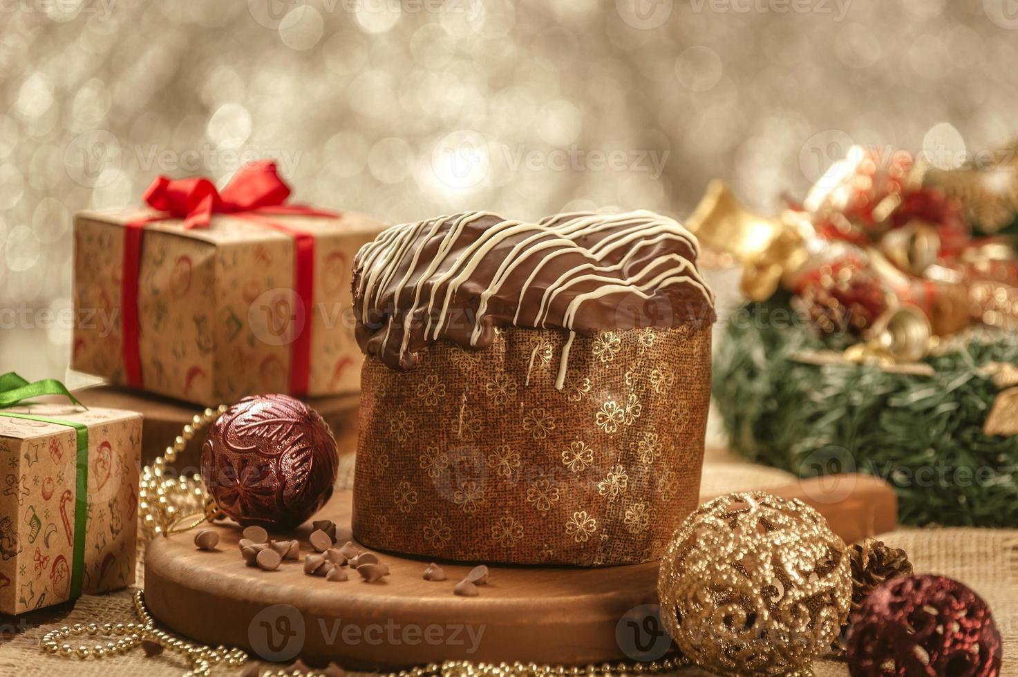 panetone de chocolate na mesa de madeira com enfeites de natal foto