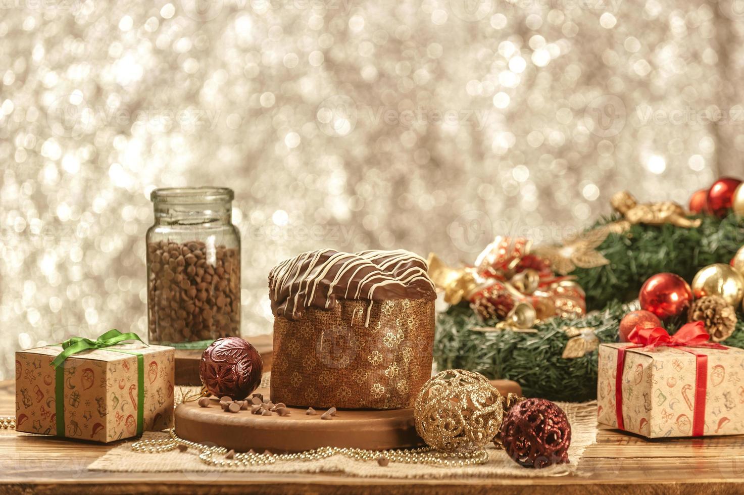 panetone de chocolate na mesa de madeira com enfeites de natal foto