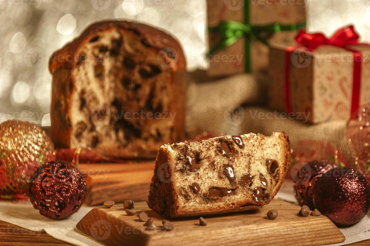 fatia de panetone de chocolate em uma tábua de madeira com enfeites de natal foto