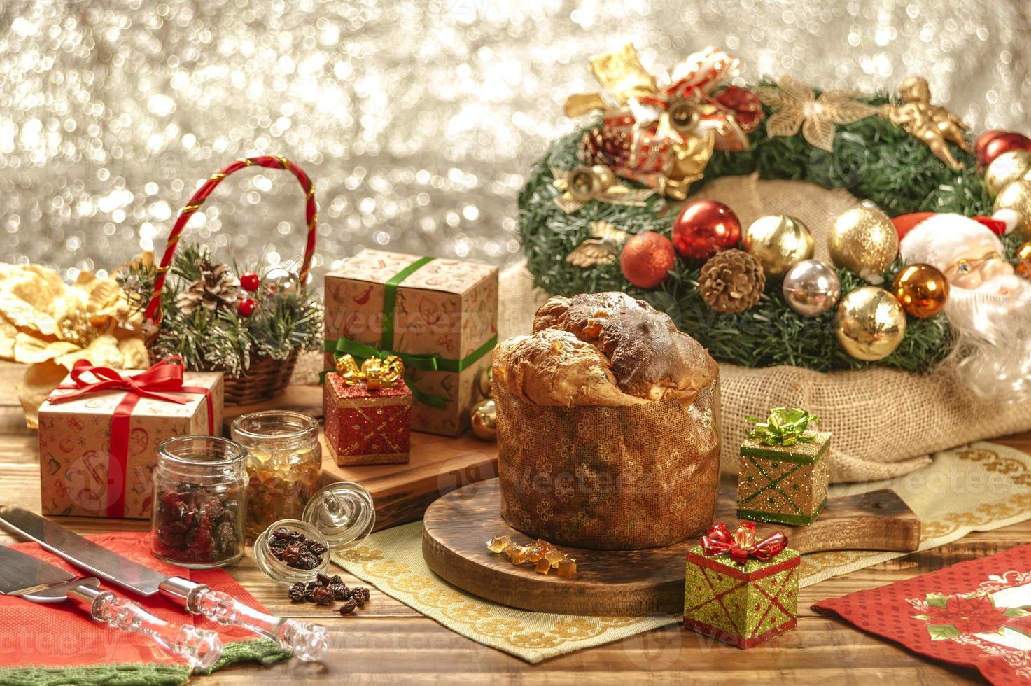 panetone, passas e cubos de frutas cristalizadas em uma tábua de madeira com enfeites de natal foto
