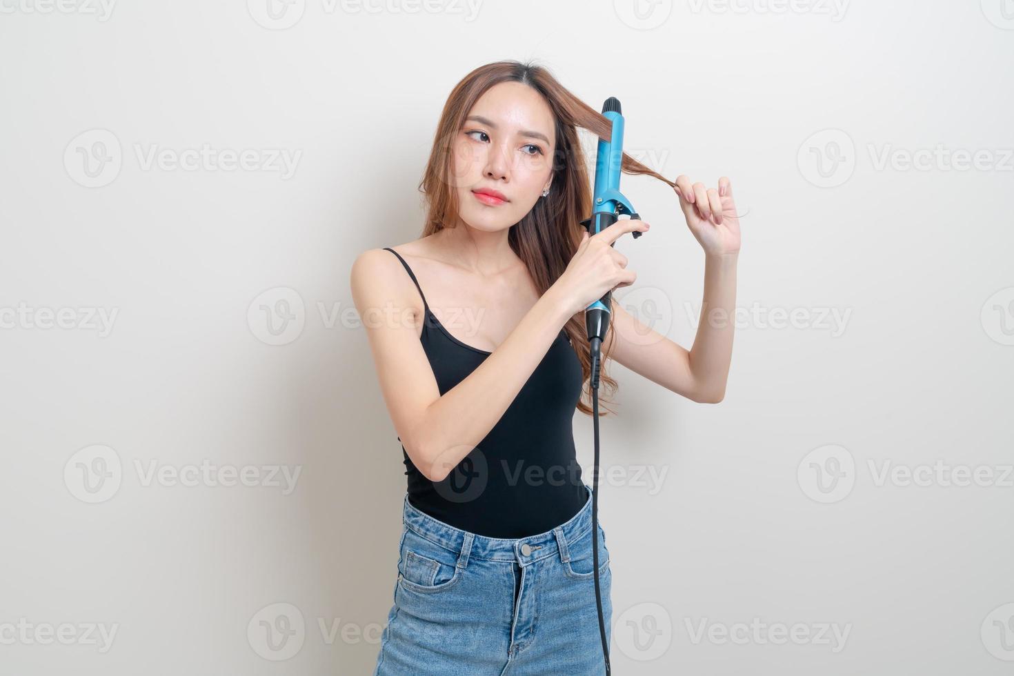 retrato de uma linda mulher asiática usando modelador de cabelo ou modelador de cachos foto