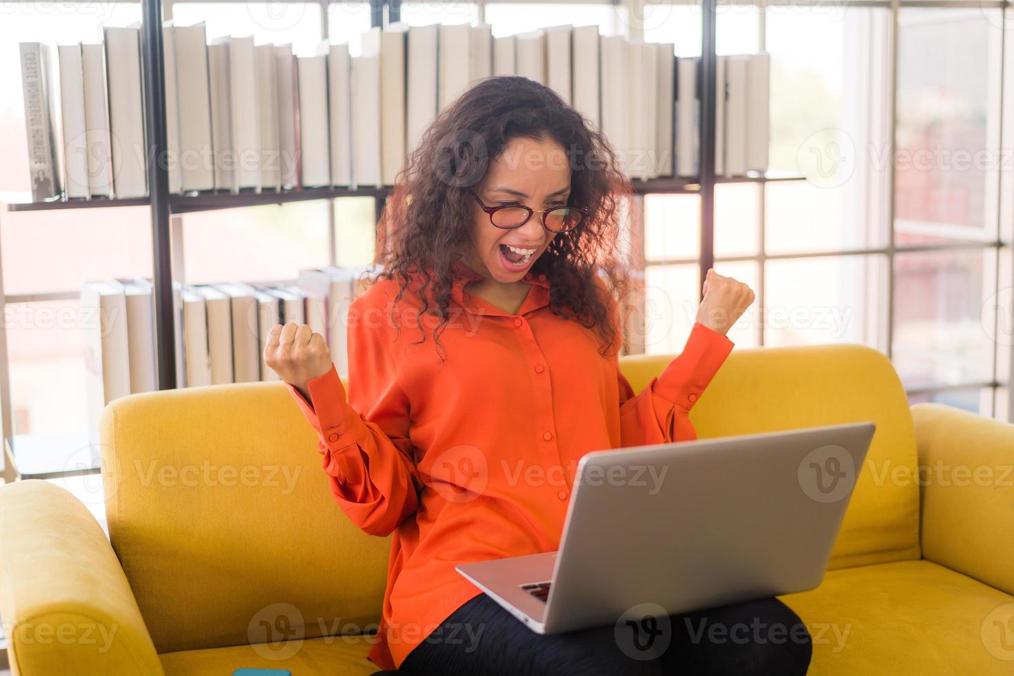 mulher latina trabalhando com laptop no sofá e sentindo-se feliz foto