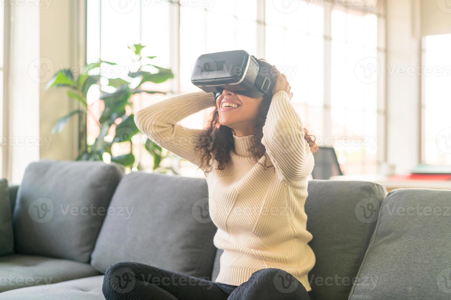 mulher latina usando um fone de ouvido de realidade virtual no sofá foto