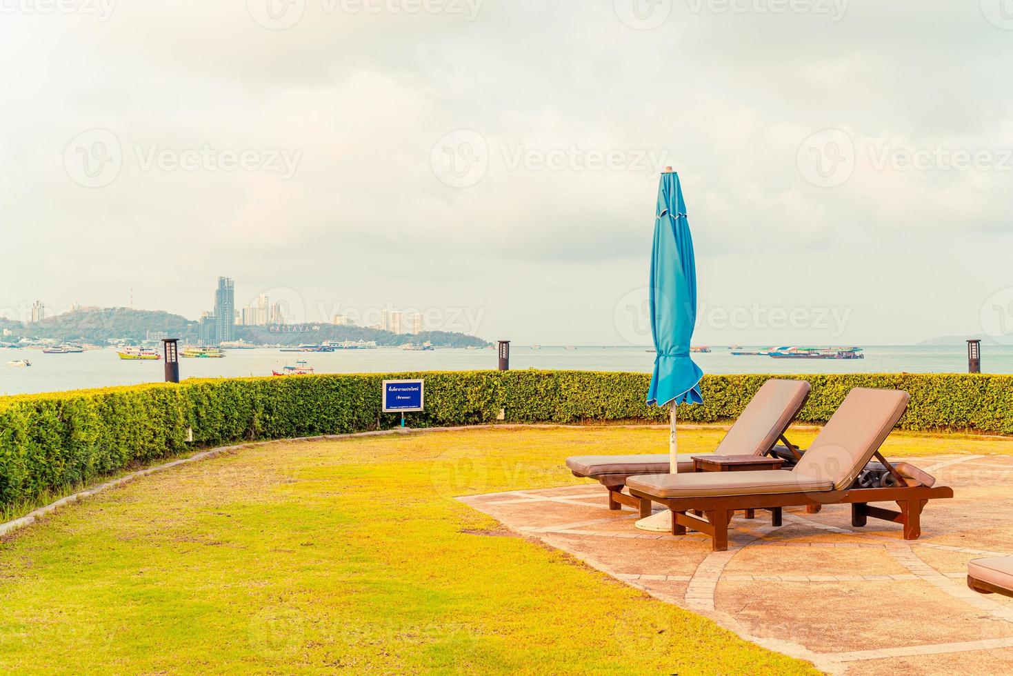 Piscina com cadeiras ou piscina com cama e guarda-sol ao redor da piscina com fundo de praia do mar foto