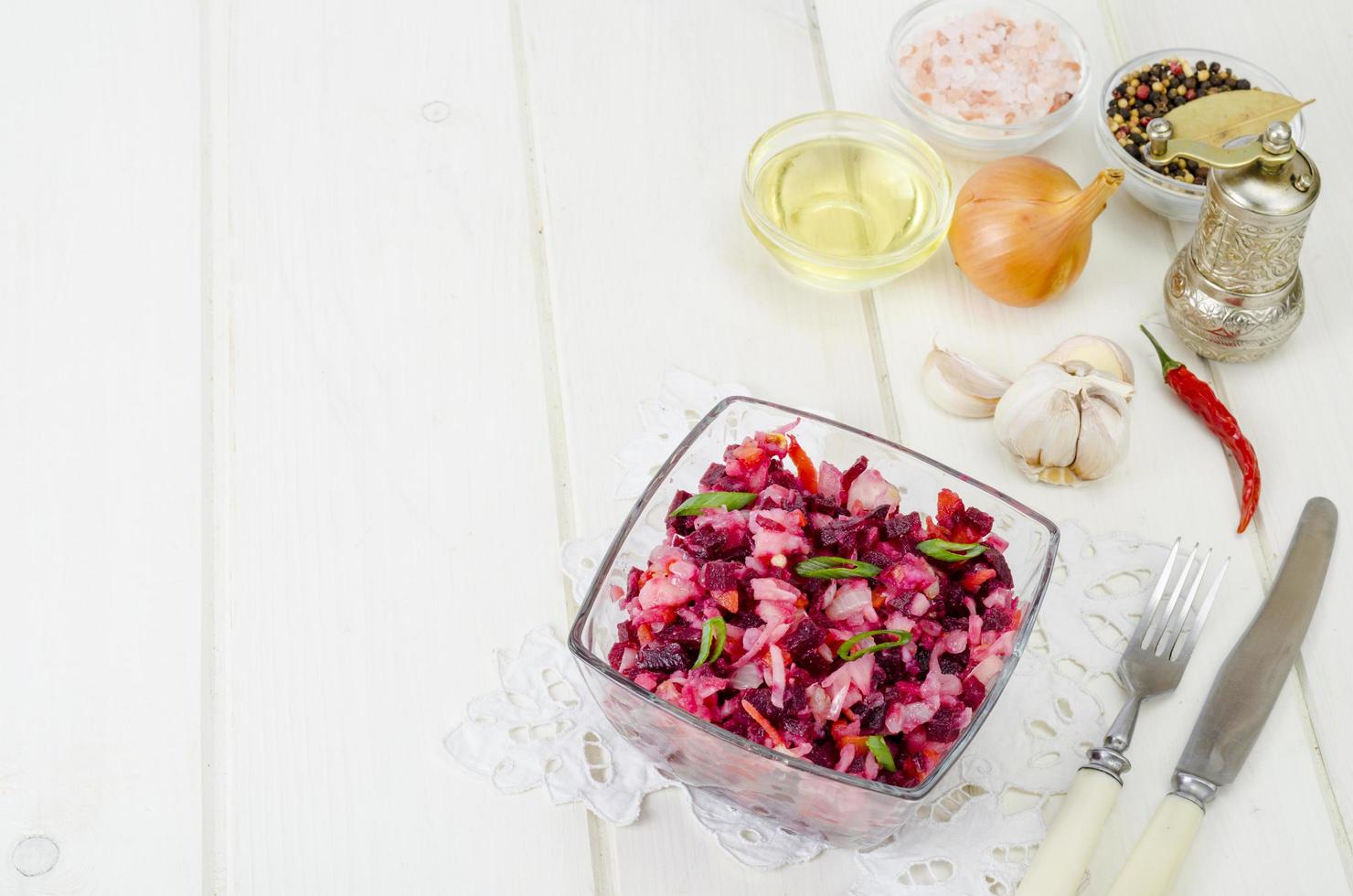 Salada de legumes com beterraba, especiarias, cebola, alho na mesa de madeira foto