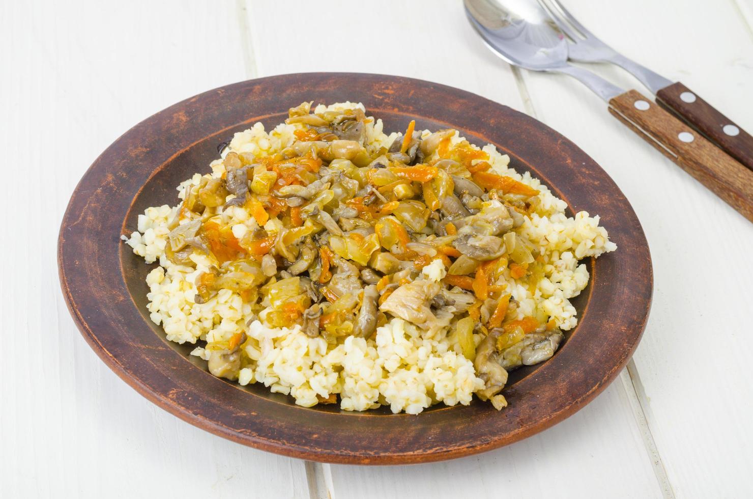 Sêmola de bulgur cozida com legumes e cogumelos cozidos, comida vegetariana. foto