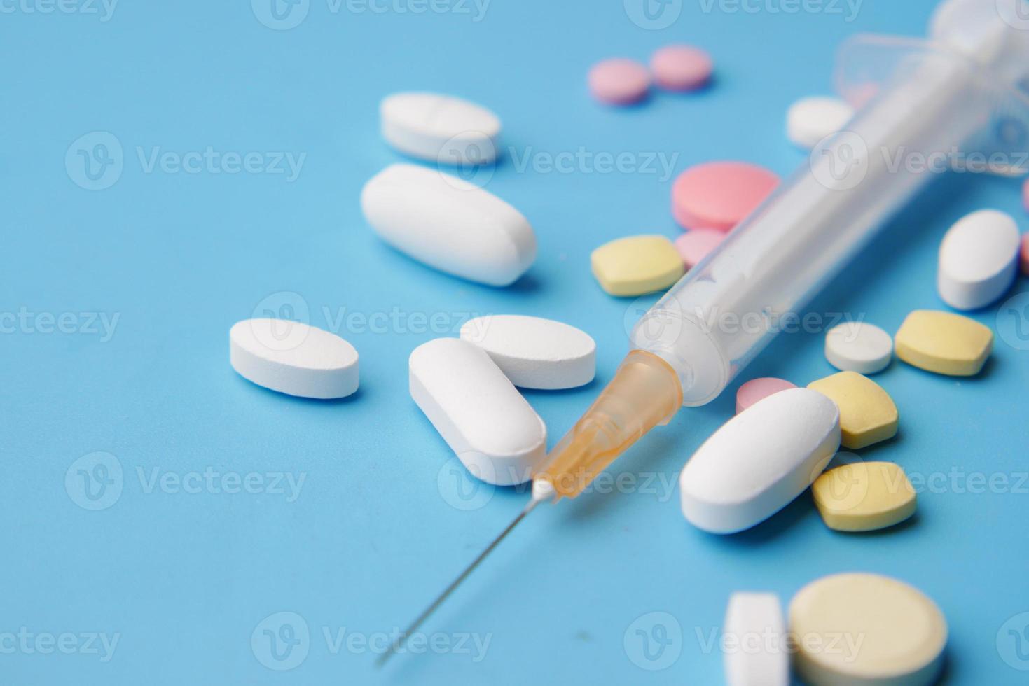 seringa e comprimidos em fundo azul, close-up foto