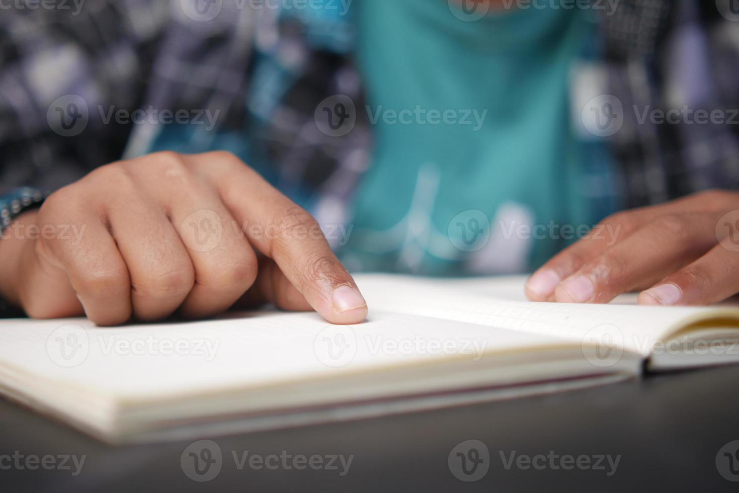 perto da mão do menino lendo um livro foto