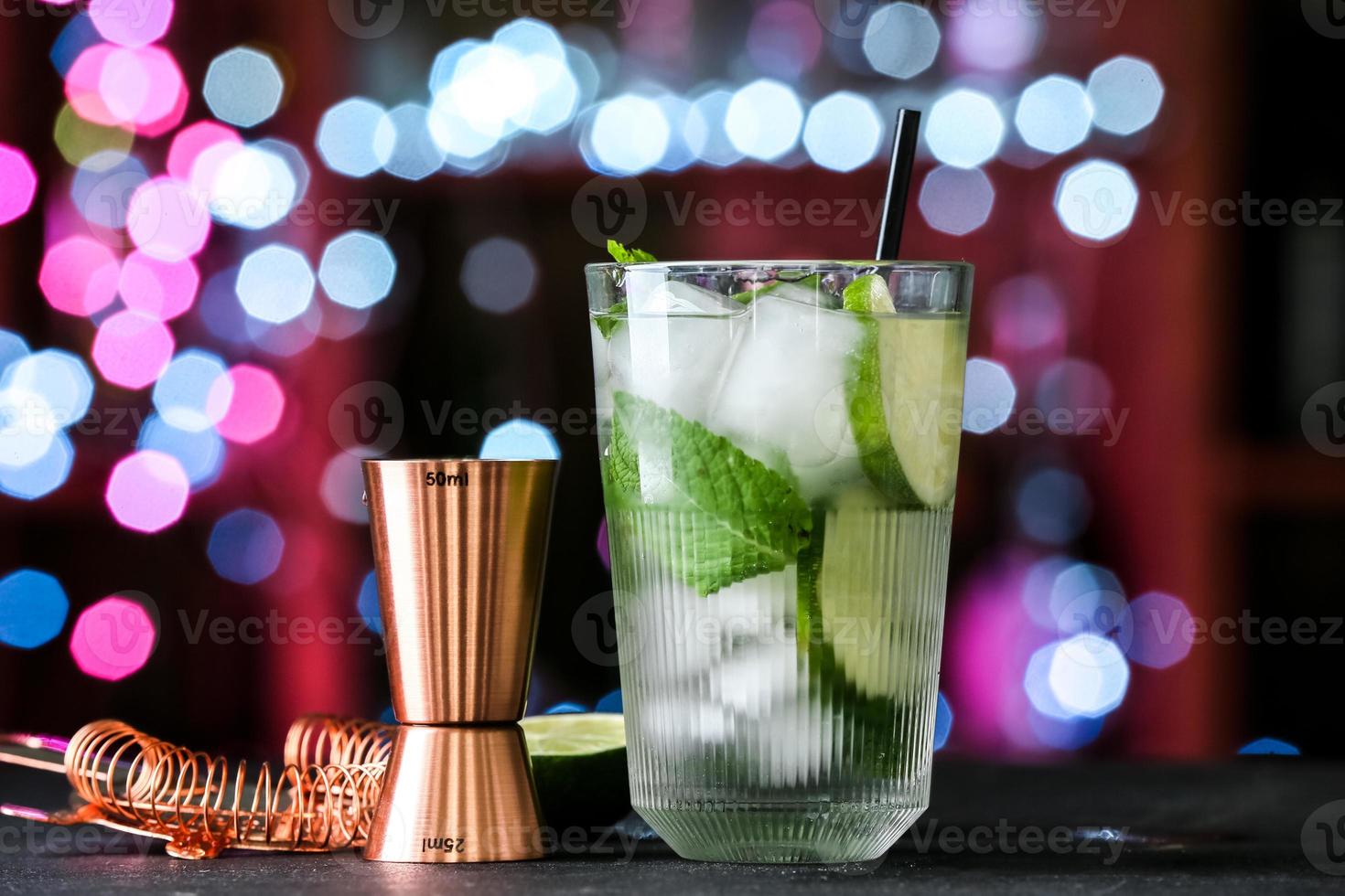 copo de mojito frio na mesa contra luzes desfocadas foto