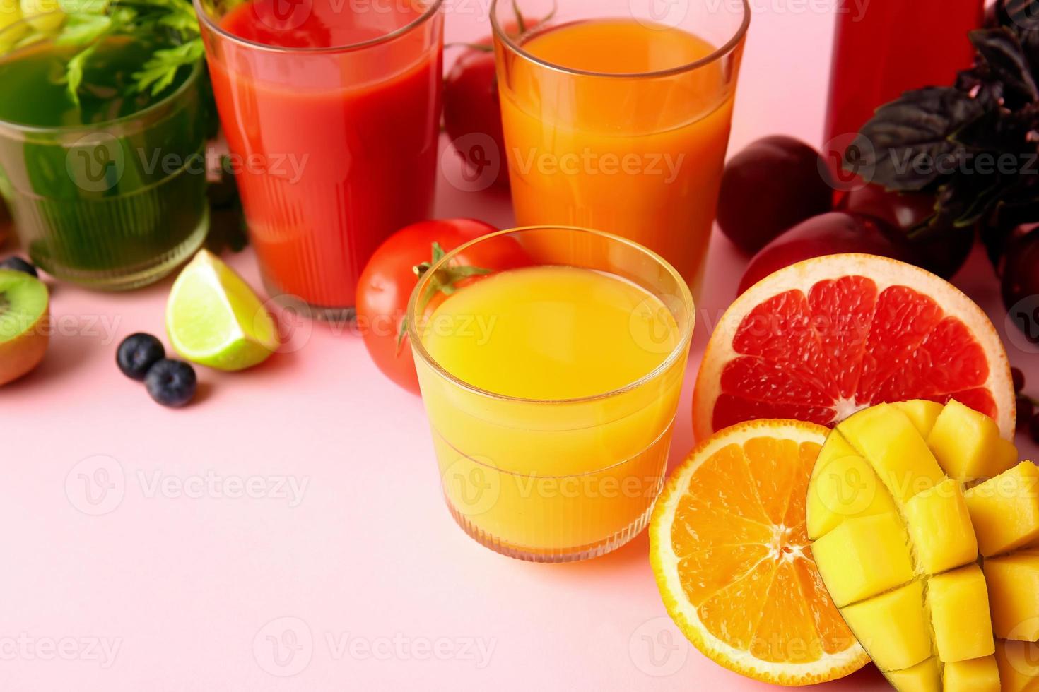 copos com suco saudável, frutas e vegetais na cor de fundo foto