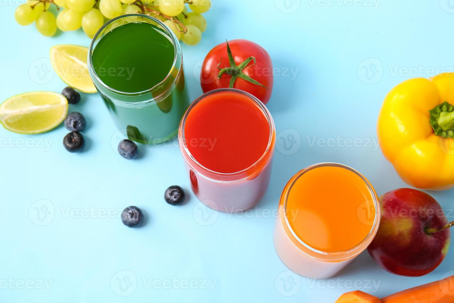 copos com suco saudável, frutas e vegetais na cor de fundo foto