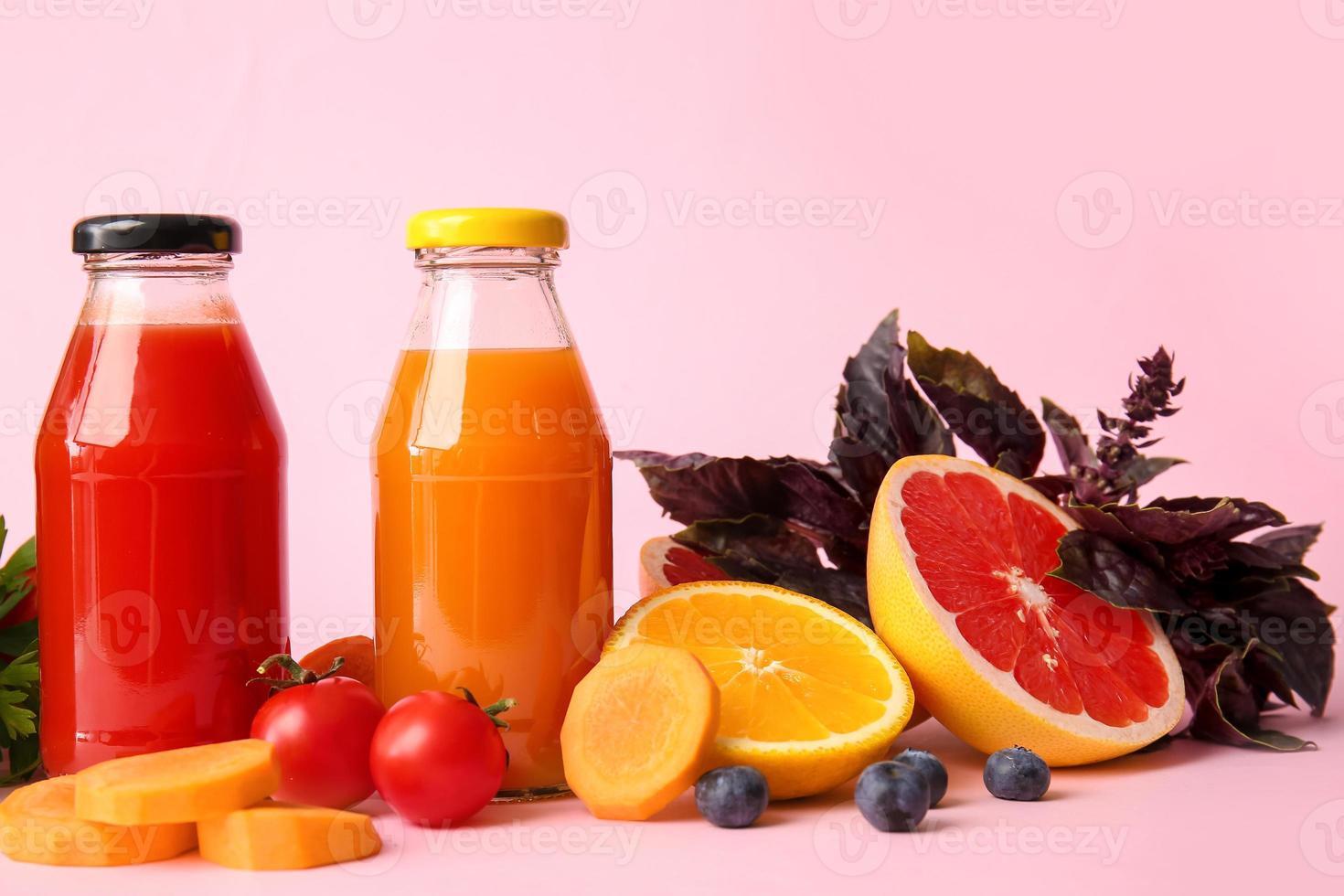 garrafas com suco saudável, frutas e vegetais na cor de fundo foto