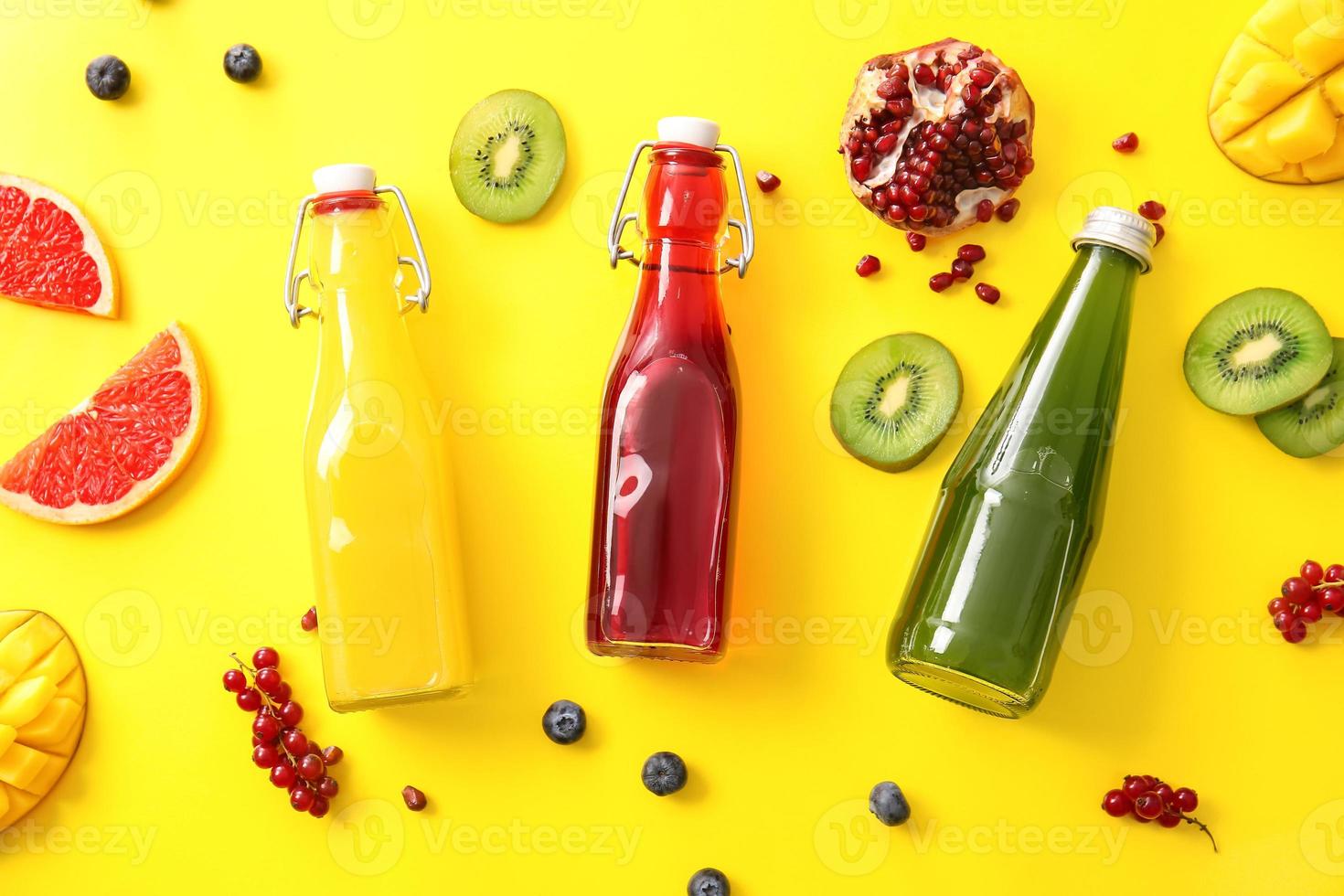 garrafas com suco saudável e frutas na cor de fundo foto