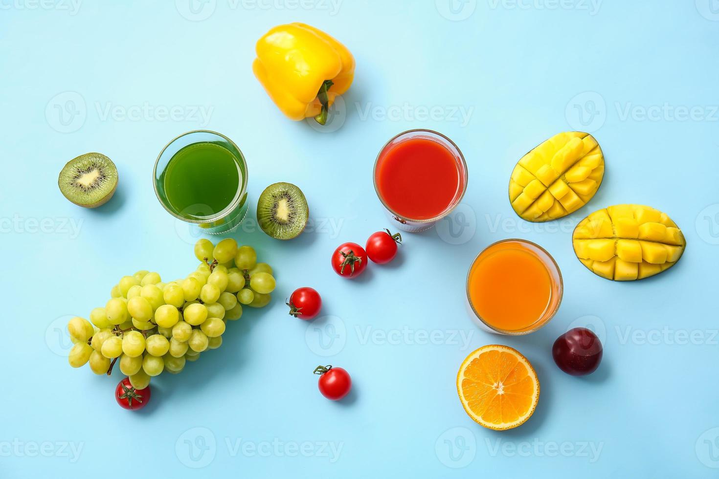 copos com suco saudável, frutas e vegetais na cor de fundo foto