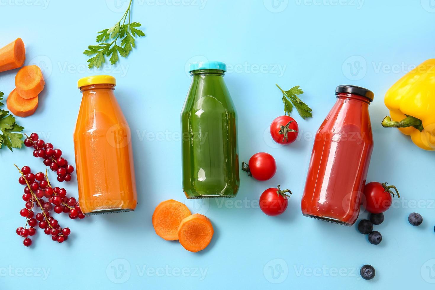 garrafas com suco saudável, frutas e vegetais na cor de fundo foto