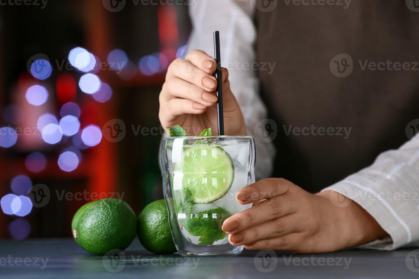 bartender com copo de mojito fresco na mesa do bar foto