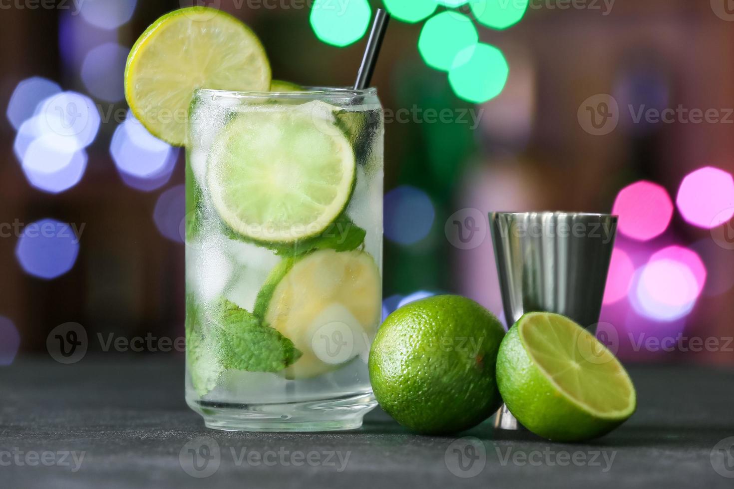 copo de mojito frio na mesa contra luzes desfocadas foto