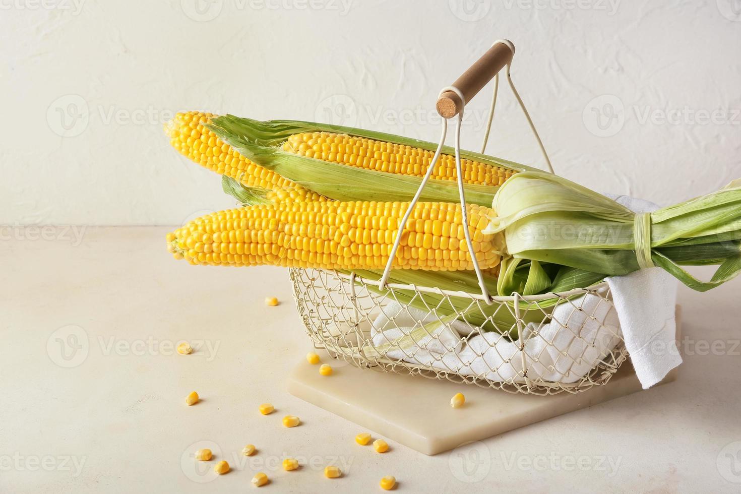 cesta com espigas de milho frescas em fundo claro foto