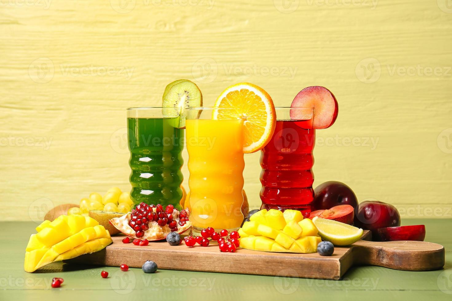 copos com suco saudável, frutas e vegetais na cor de fundo de madeira foto