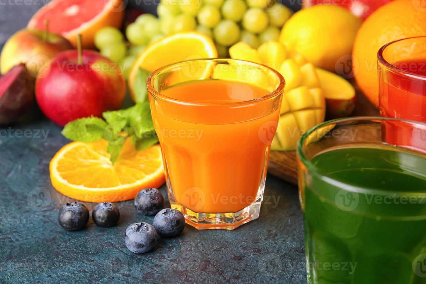 copos com sucos saudáveis, frutas e vegetais em fundo escuro foto