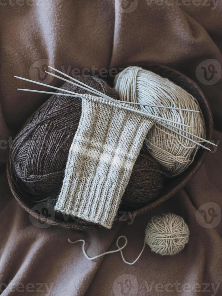 mão tricotado meias com agulhas e fio bola dentro uma cesta. foto