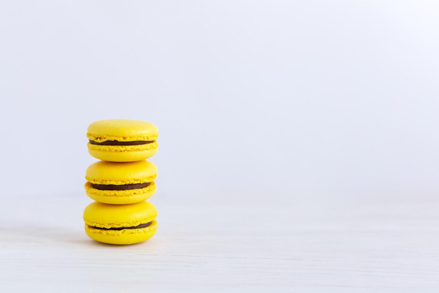 três amarelo francês macarons em uma de madeira mesa. banana macarons com chocolate creme. foto