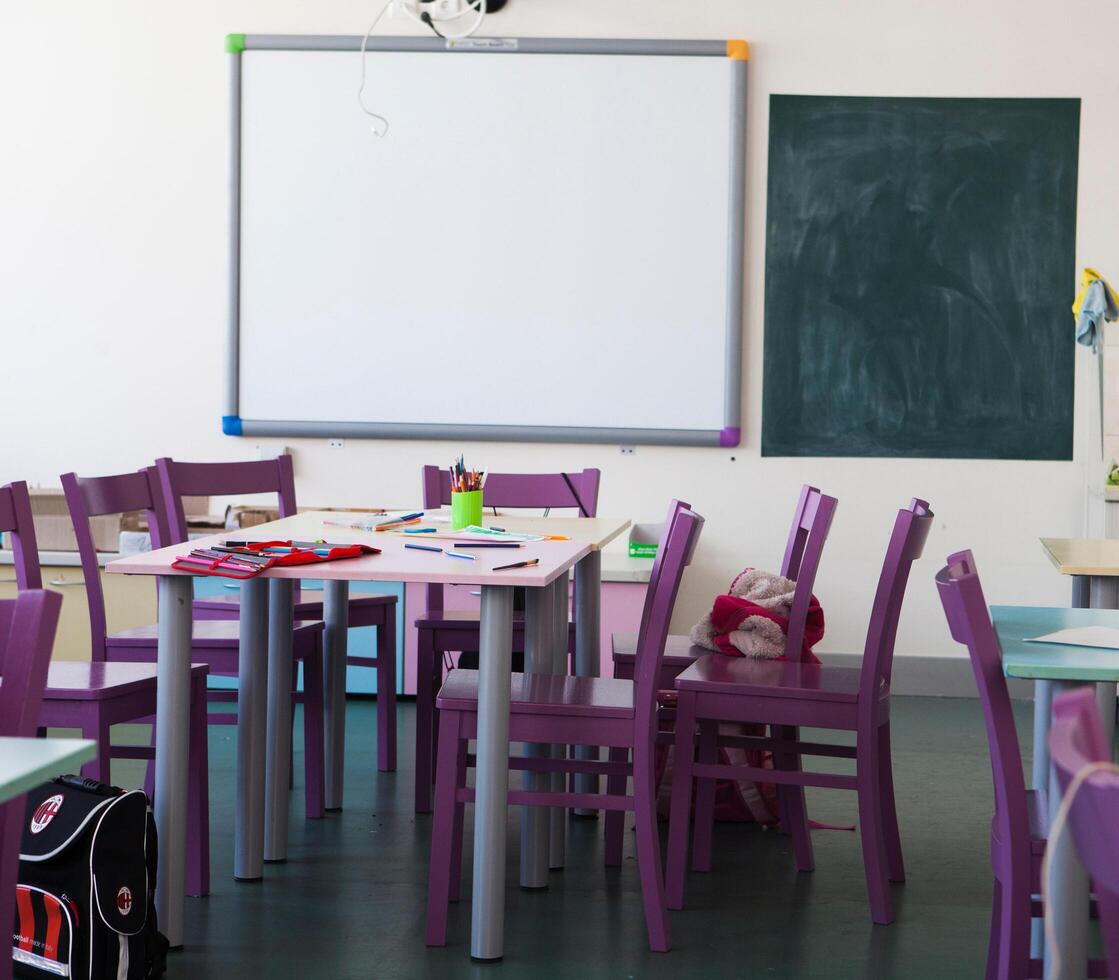 uma Sala de aula com roxa cadeiras e uma quadro-negro em a muro. foto