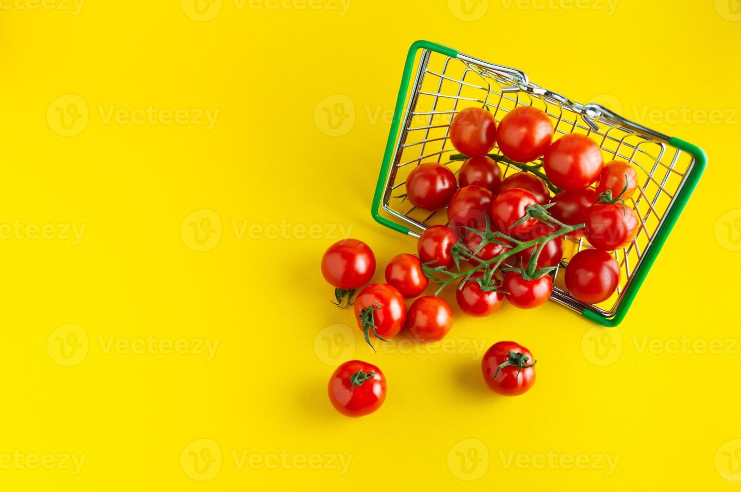 tomates cereja espalhados em uma cesta em um fundo amarelo brilhante com um lugar vazio para uma inscrição. foto