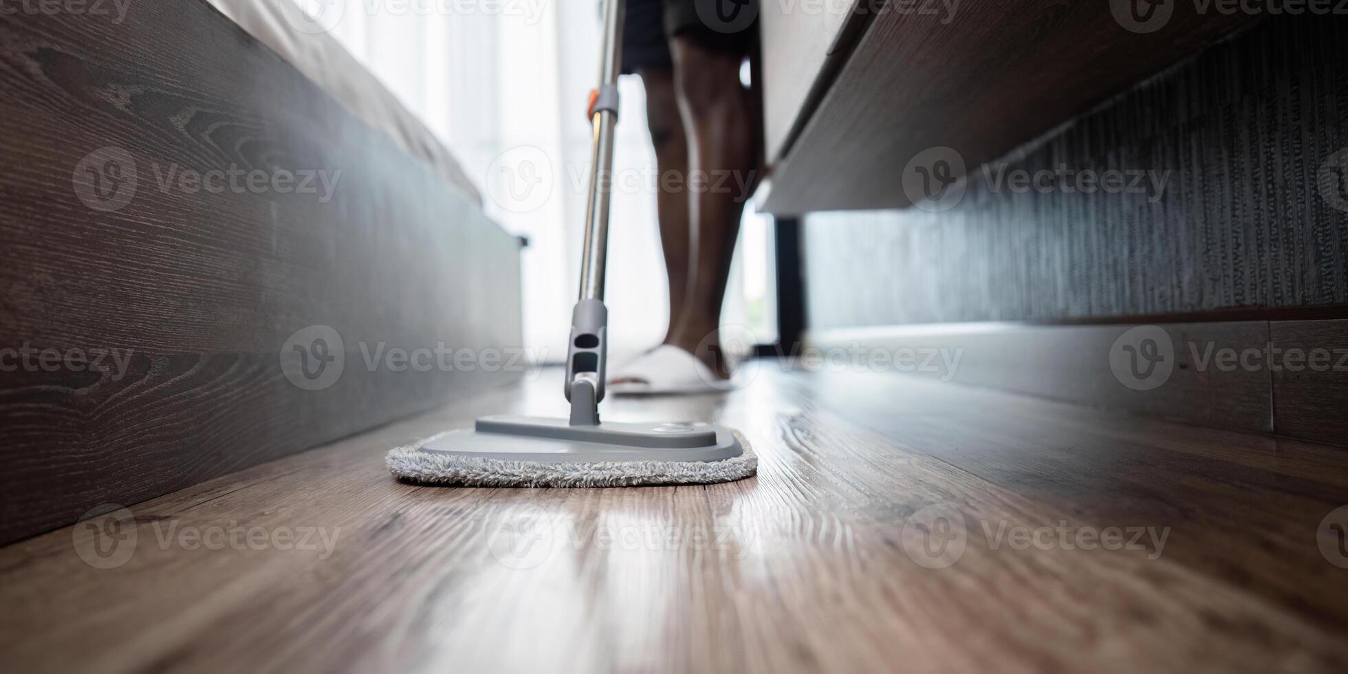 africano americano homem jovem lavar a chão com uma esfregão dentro a quarto às casa foto
