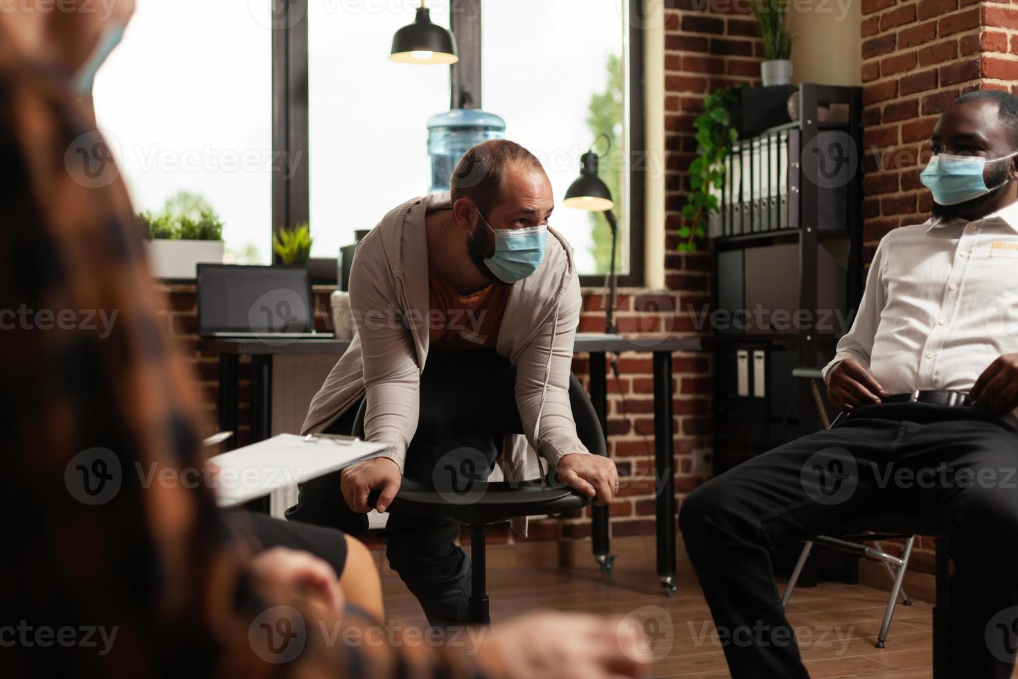 homem com máscara facial conversando com o grupo em um programa de reunião sobre questões de saúde foto