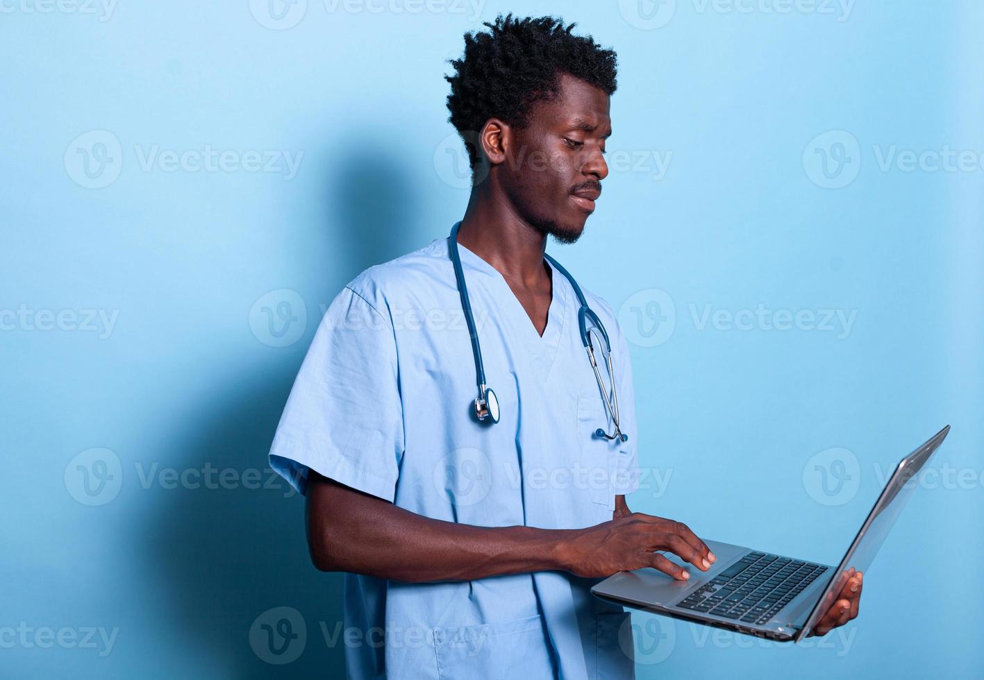 assistente médico afro-americano olhando para o laptop na mão foto