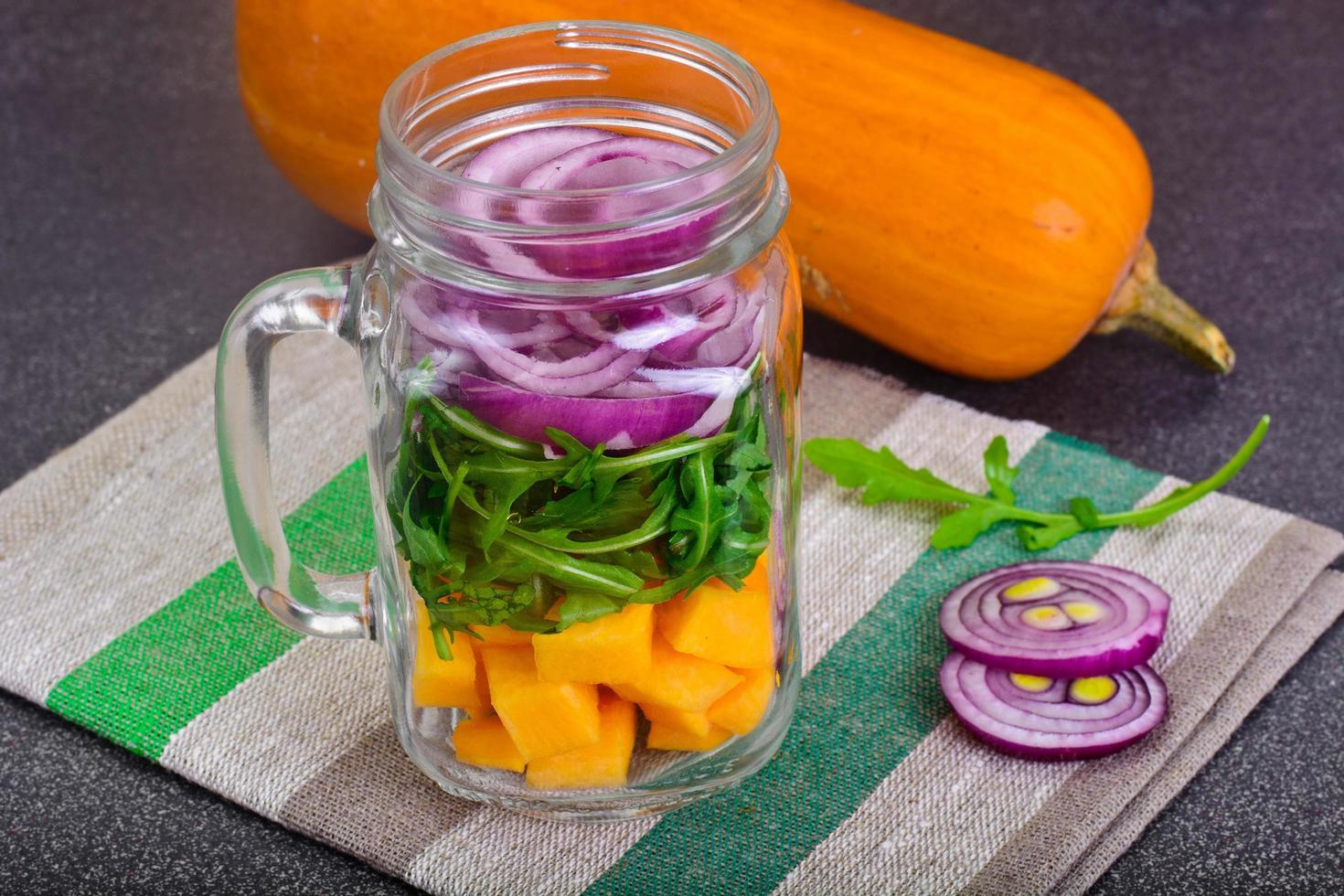 salada com abóbora, rúcula e cebola roxa em frasco de vidro foto