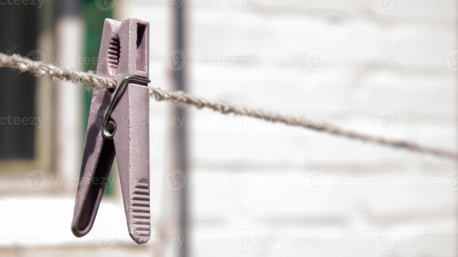 prendedores de roupa de plástico pendurados em uma linha na corda. corda ao ar livre, em um fundo desfocado em um jardim ensolarado. varal na rua. prendedores de roupa. foto