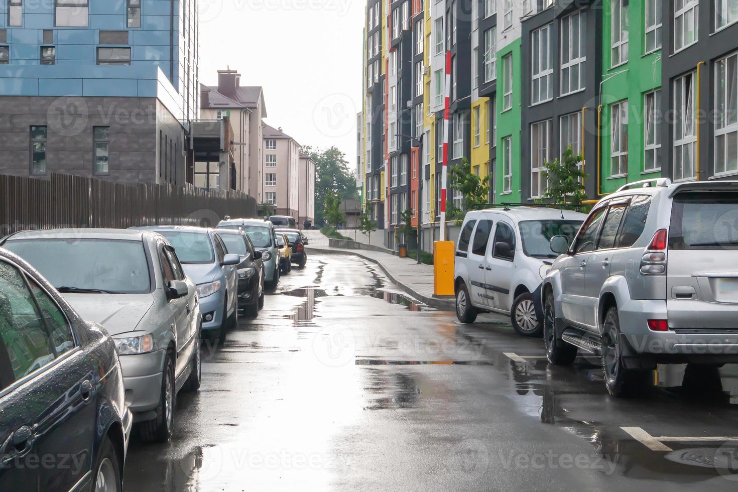 rua em uma cidade sem pessoas com carros estacionados em tempo chuvoso. chuva na estrada. chuva e carros. fundo de carros estacionados em uma rua chuvosa da cidade. carros estacionados simétricos. foto