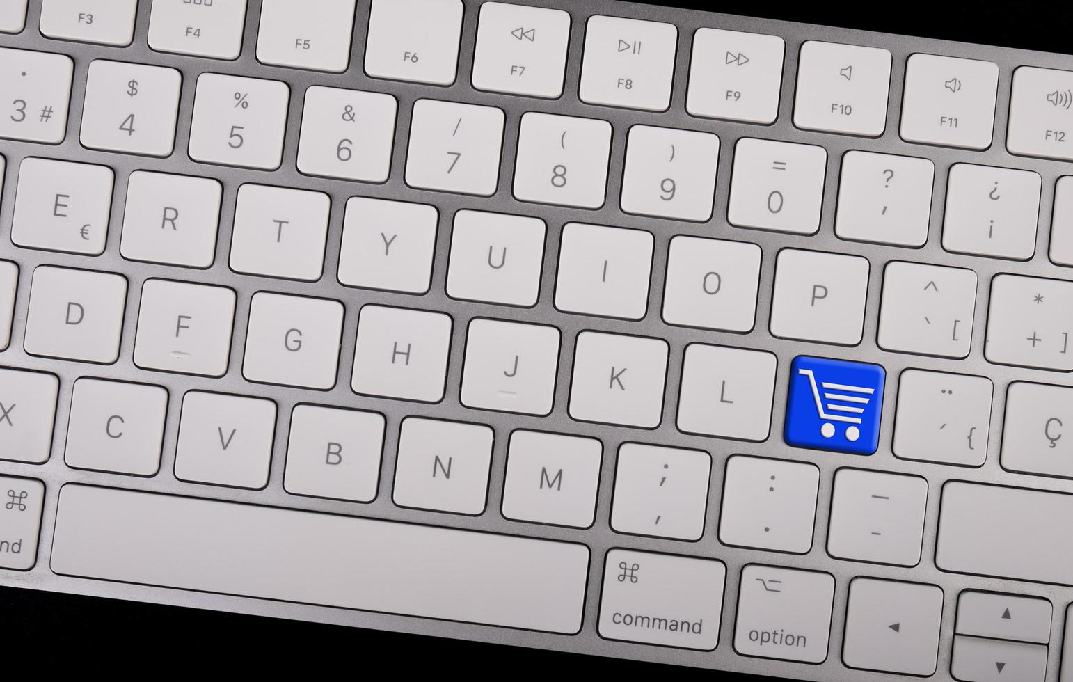 teclado de notebook com ícone do carrinho de compras na chave. conceito de e-commerce foto