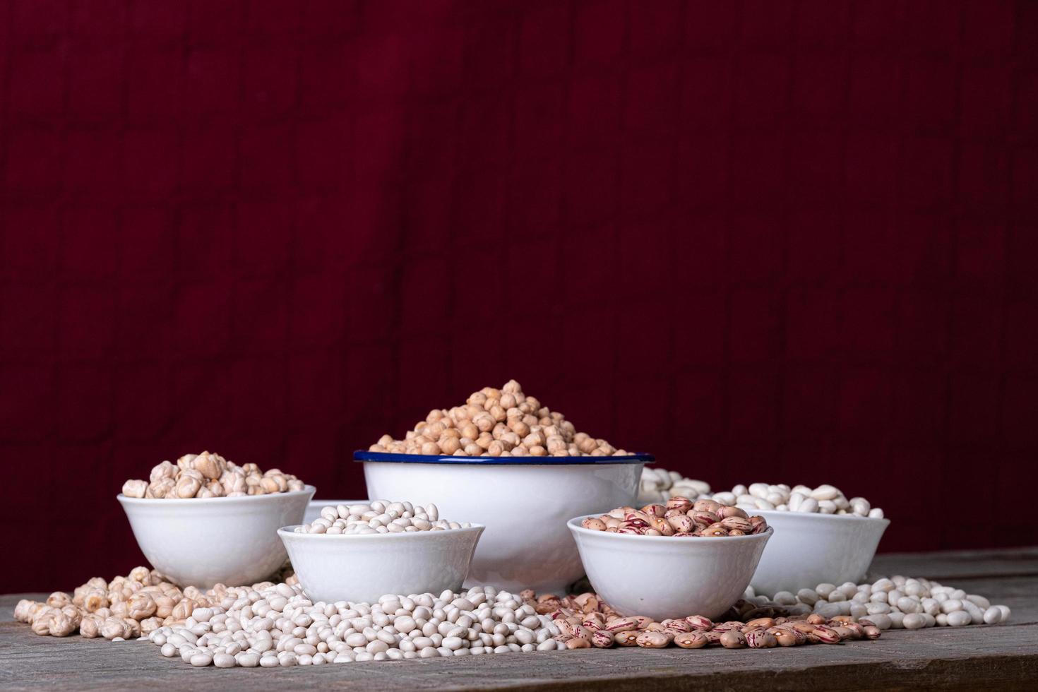 taças brancas com uma variedade de leguminosas em frente a um fundo vermelho foto