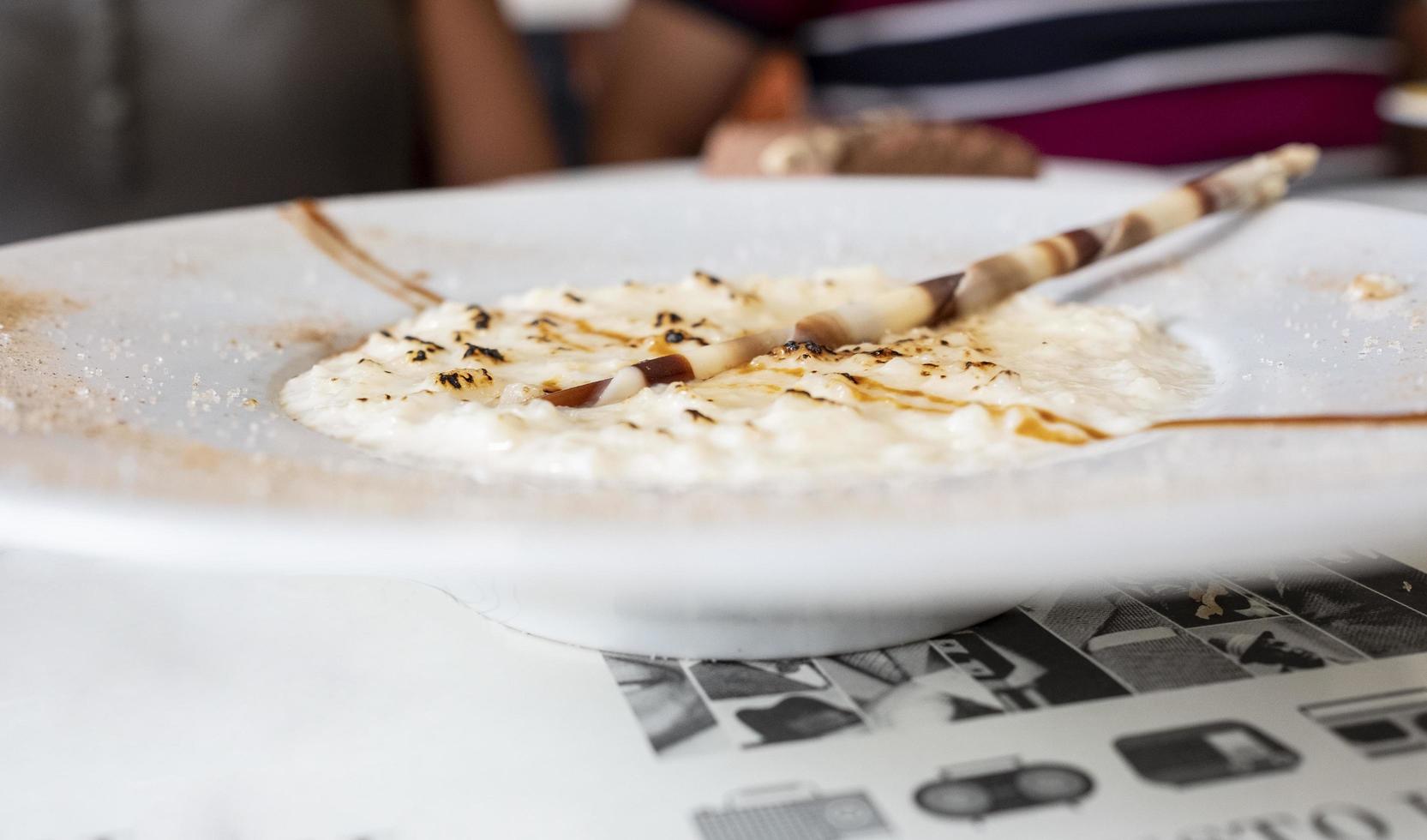 pudim de arroz com gotas de chocolate e açúcar queimado em prato branco foto