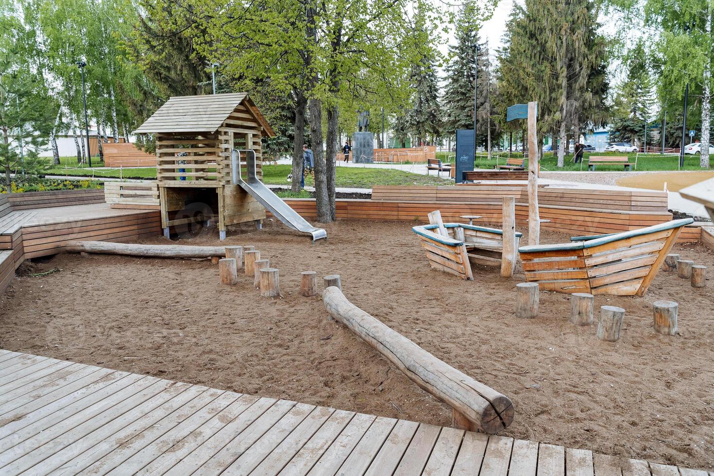 crianças Parque infantil do ampla tamanhos, caixa de areia dentro a quintal, de madeira barco para jogos, uma casa com uma deslizar, descansar com uma criança em a rua. foto