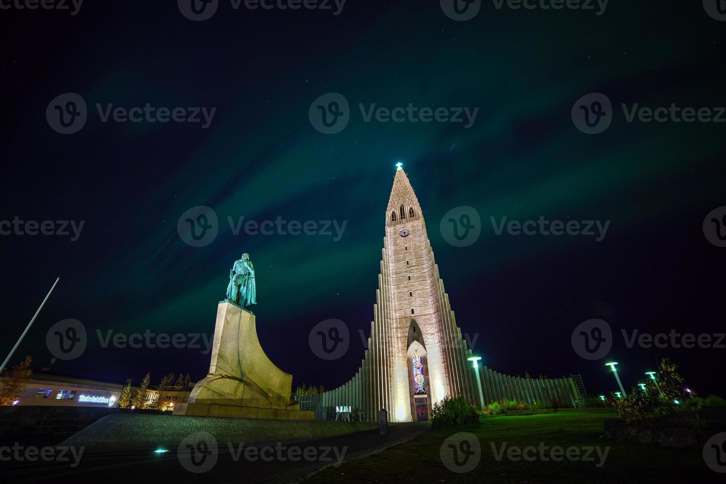 luzes do norte brilhando sobre a igreja em reykjavik foto