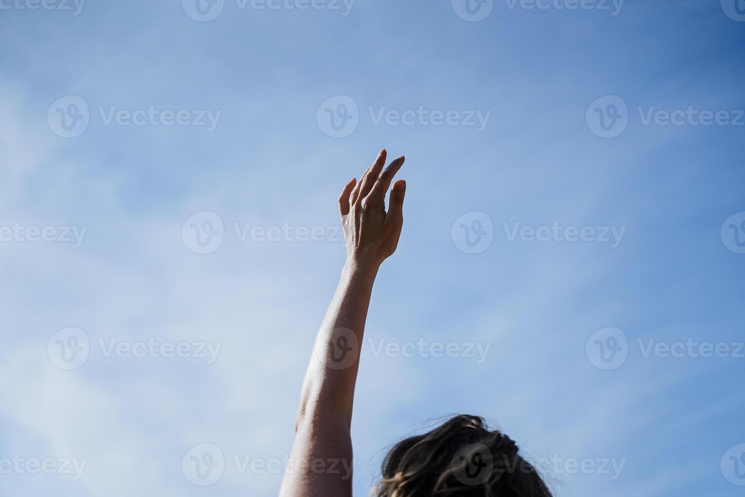 uma mulher mão é estendido para cima contra a azul céu, uma gesto do felicidade e alegria, para Conheça a Sol dentro a manhã às alvorecer, pólen mãos, parte do a corpo. foto