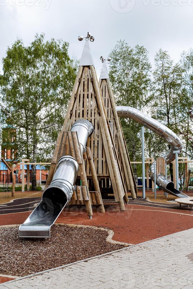 uma ampla Esportes jogar complexo para crianças dentro a aberto ar, uma crianças Parque infantil fez do madeira dentro a cidade parque, uma metal deslizar, uma pirâmide do Histórico, a atração para crianças. foto