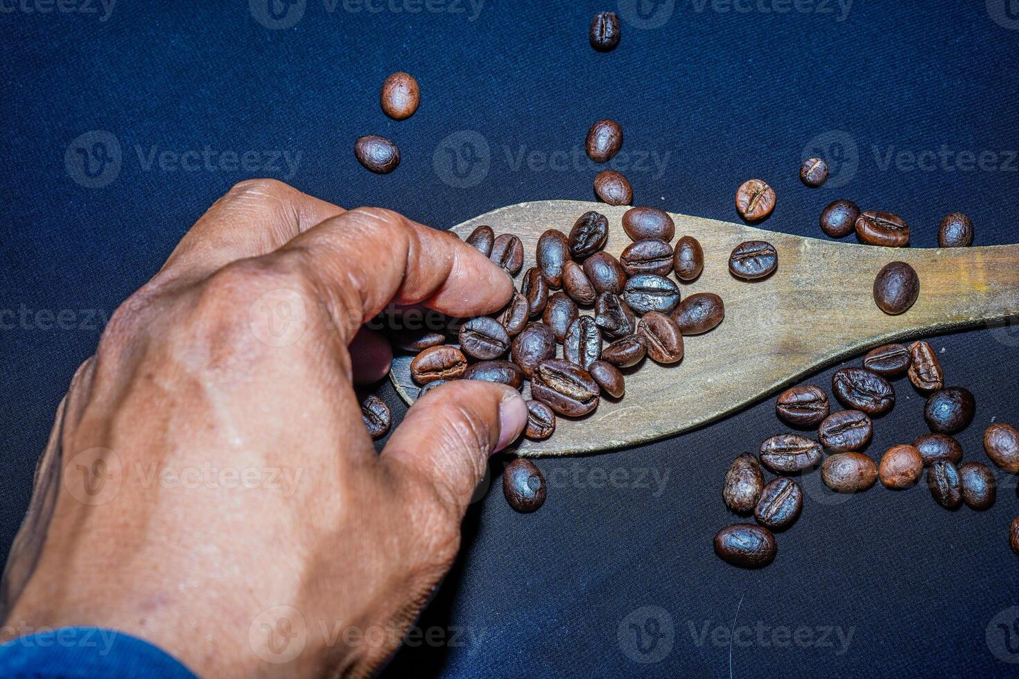 Preto café feijões estão visto fechar acima com uma de madeira colher em uma Preto pano. foto