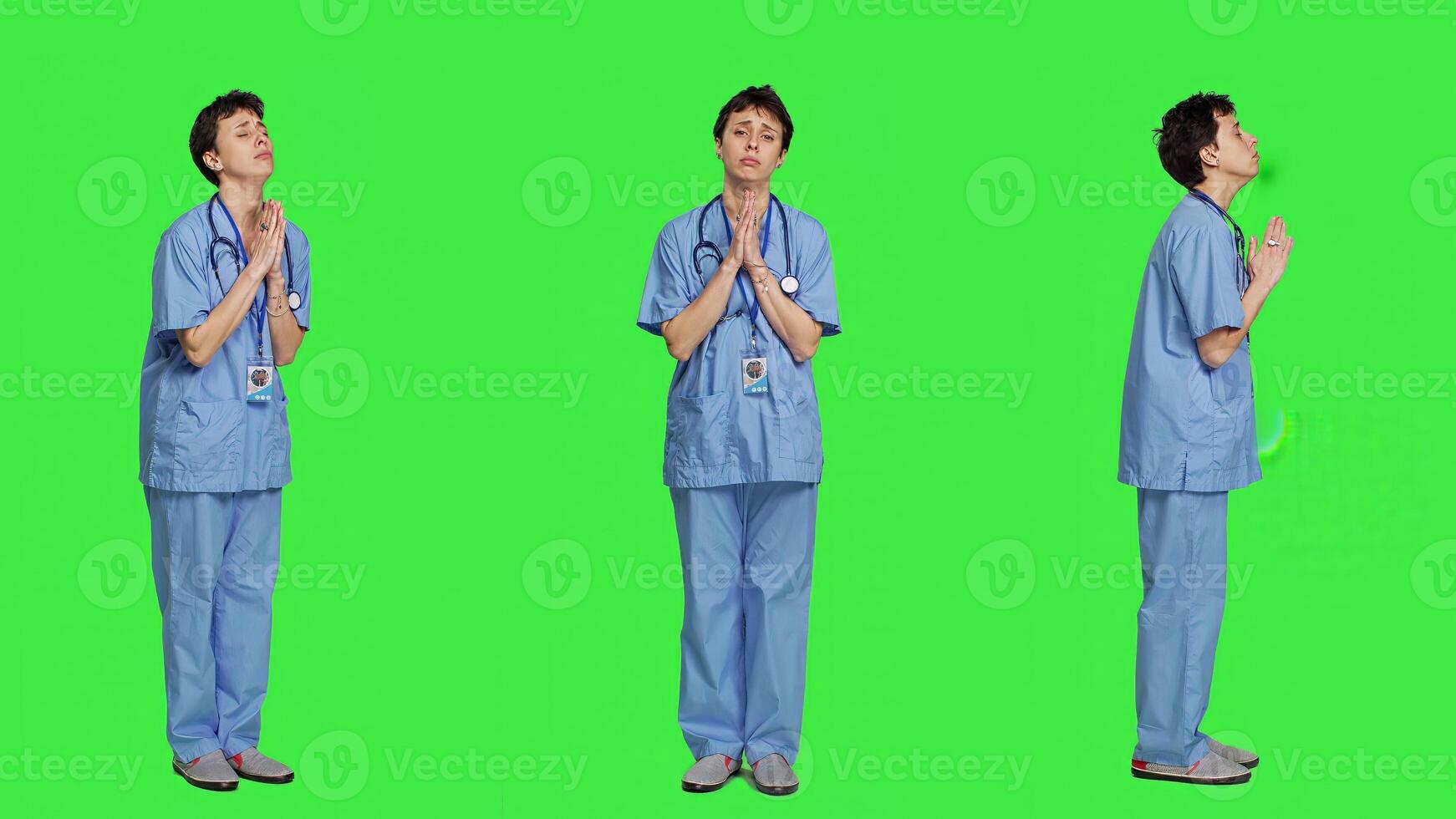 médico assistente ser esperançoso Rezar para Boa sorte contra tela verde, detém mãos dentro uma oração placa e tendo crença dentro espiritualidade. jovem cristão enfermeira com fé dentro meditação. Câmera uma. foto