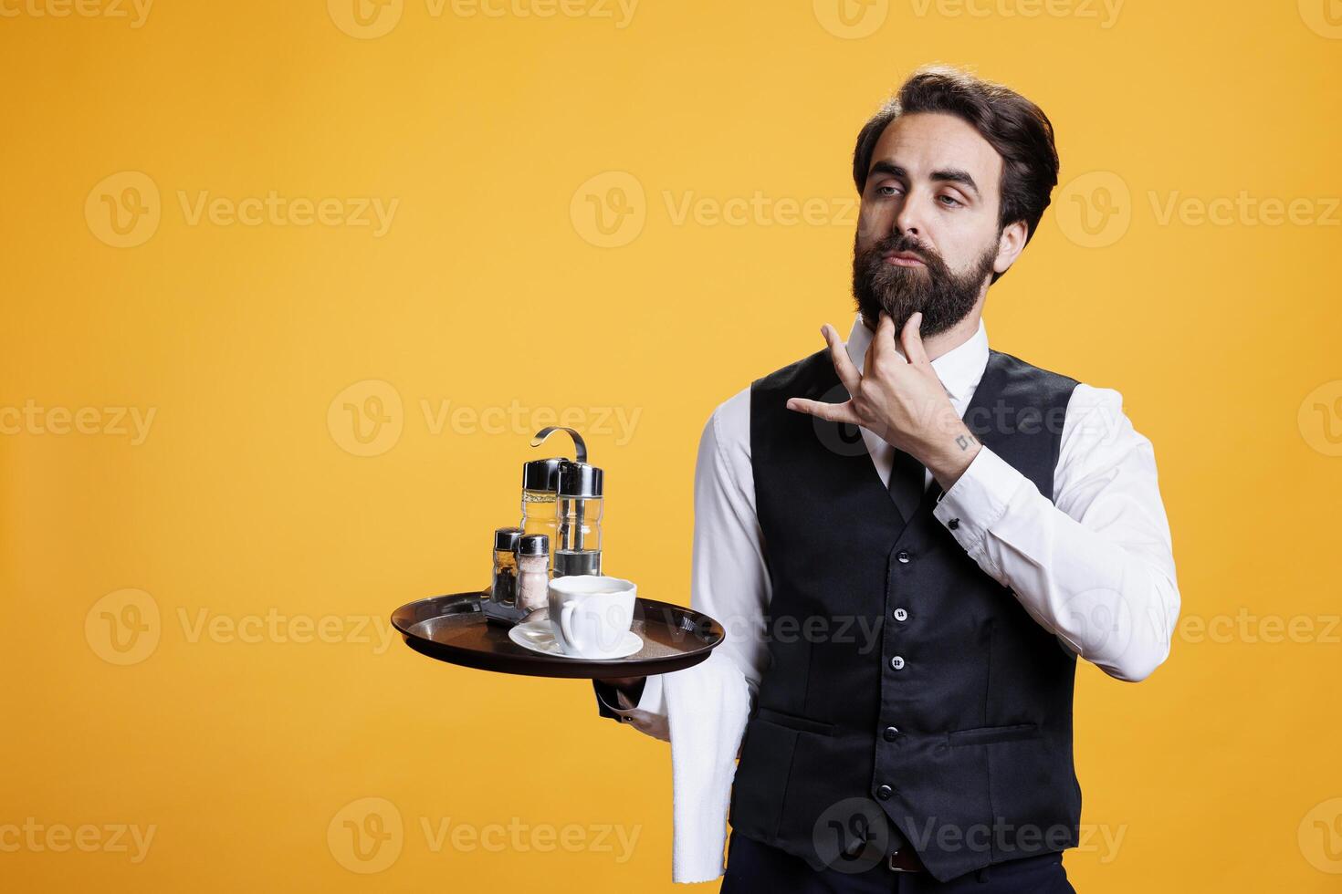 elegante mordomo com terno e gravata dentro estúdio, agindo confiante enquanto ele detém Comida prato com talheres e café copo para servir clientes. profissional especializado garçom posando em Câmera, sentindo-me dedicada. foto