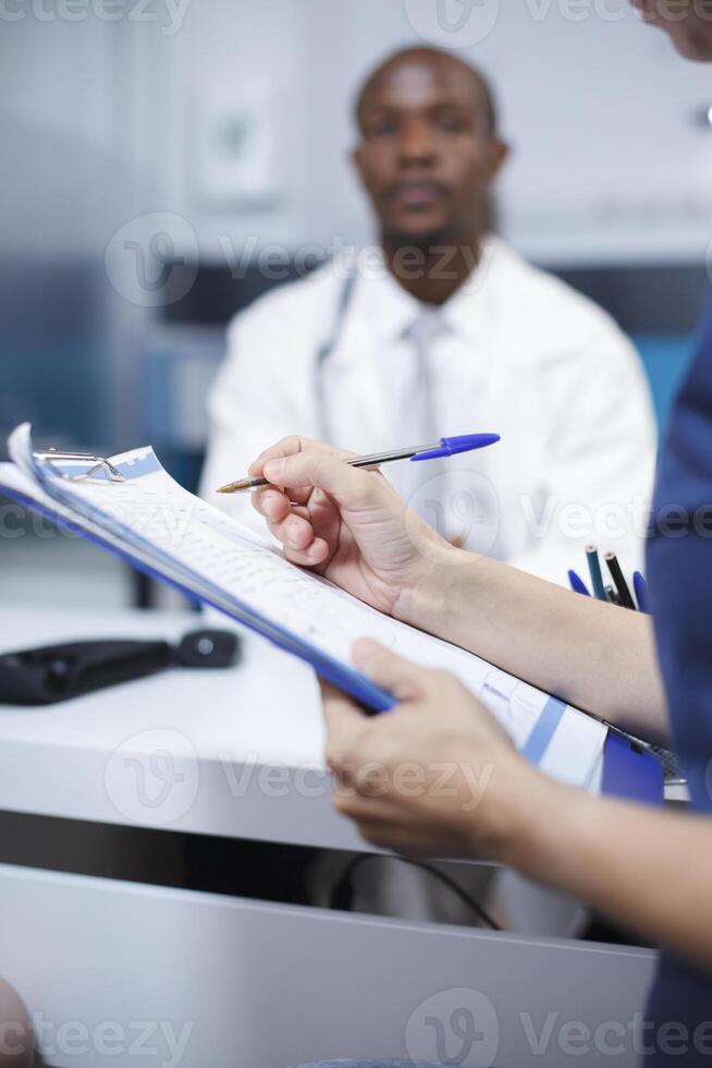 fechar-se tiro do uma fêmea paciente o preenchimento Fora papelada para dela médico exame com a médico às a hospital. qualidade cuidados de saúde e adendo estão forneceu dentro isto consulta. foto