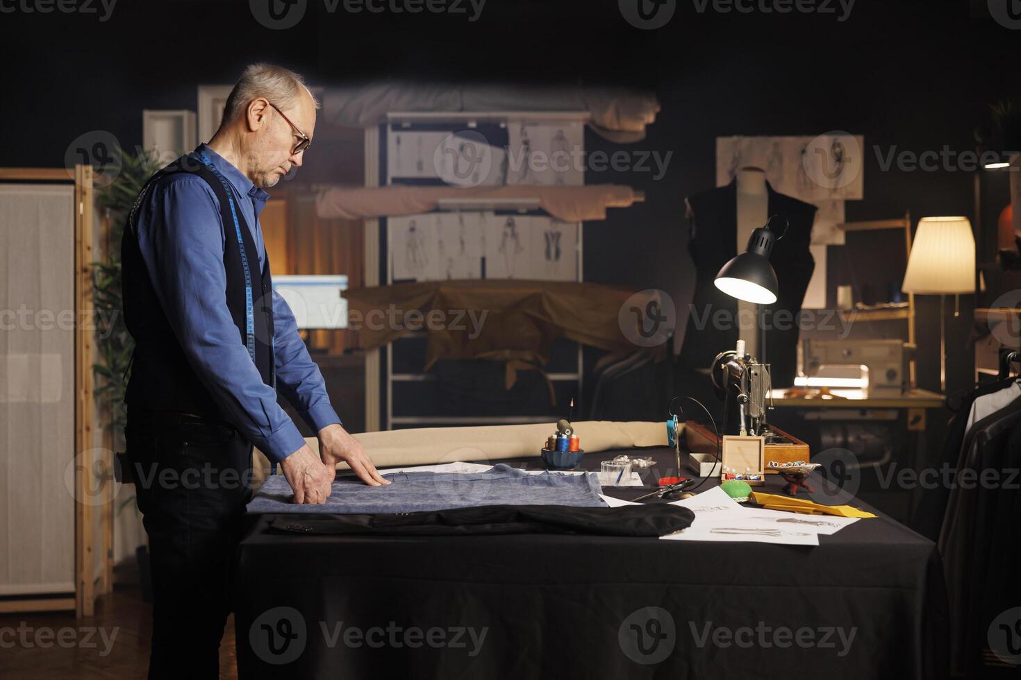 idosos com experiência artesão sozinho dentro profissional alfaiataria estúdio, pensando do futuro moda coleção Projeto. Senior costureiro dentro atelier fazer compras área de trabalho fabricação roupas foto