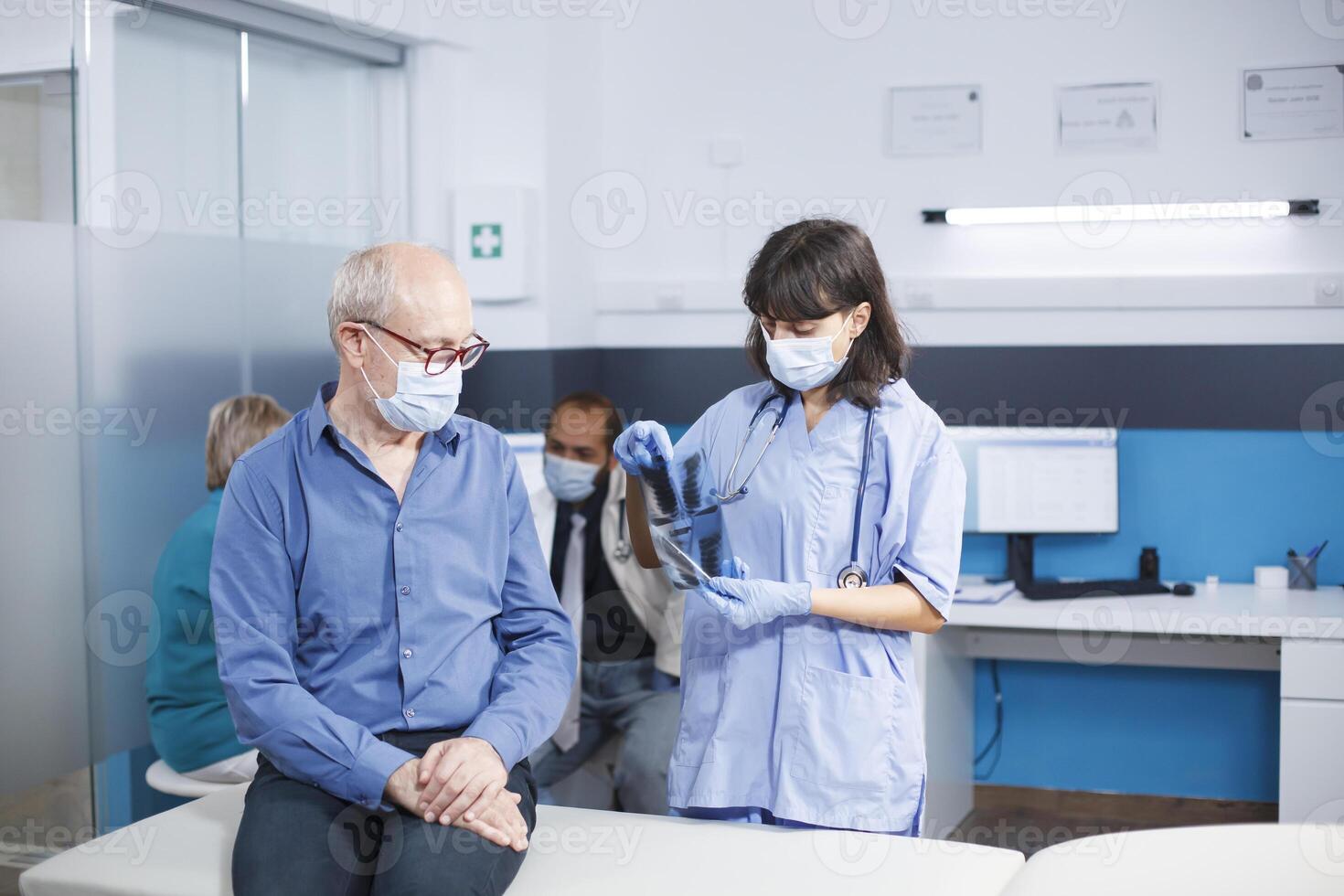 durante coronavírus epidemia, enfermeira praticante agarra ct Varredura dados durante médico consulta com idosos cara. cuidados de saúde profissional descreve radiografia diagnóstico e pulmão terapia. foto